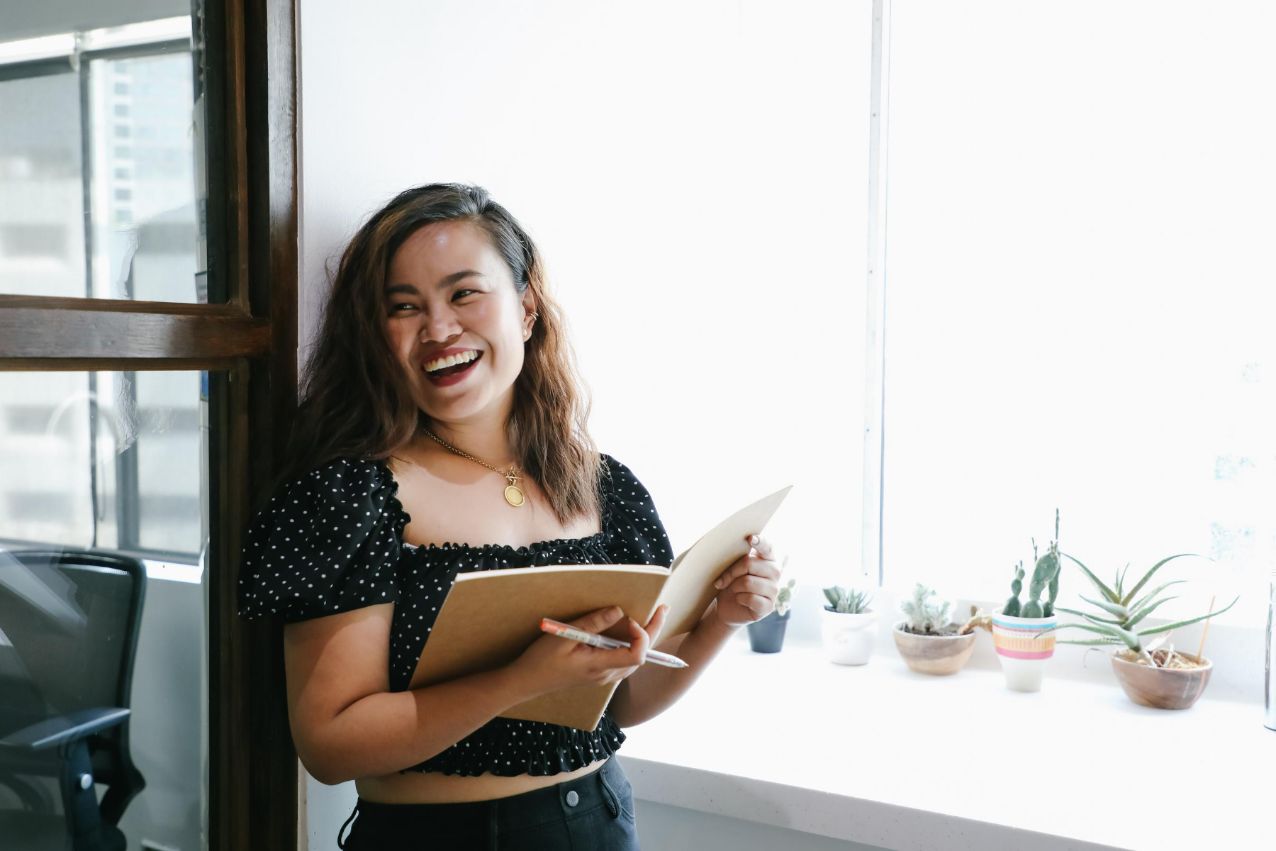 How to choose a fulfilling career. Young woman at work smiling happily and holding a pen and book.