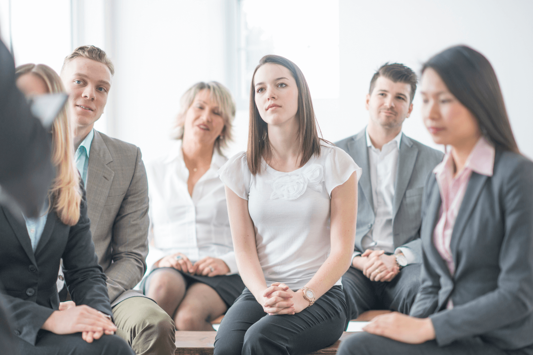 six people sitting attentively as a man conducts a group interview.