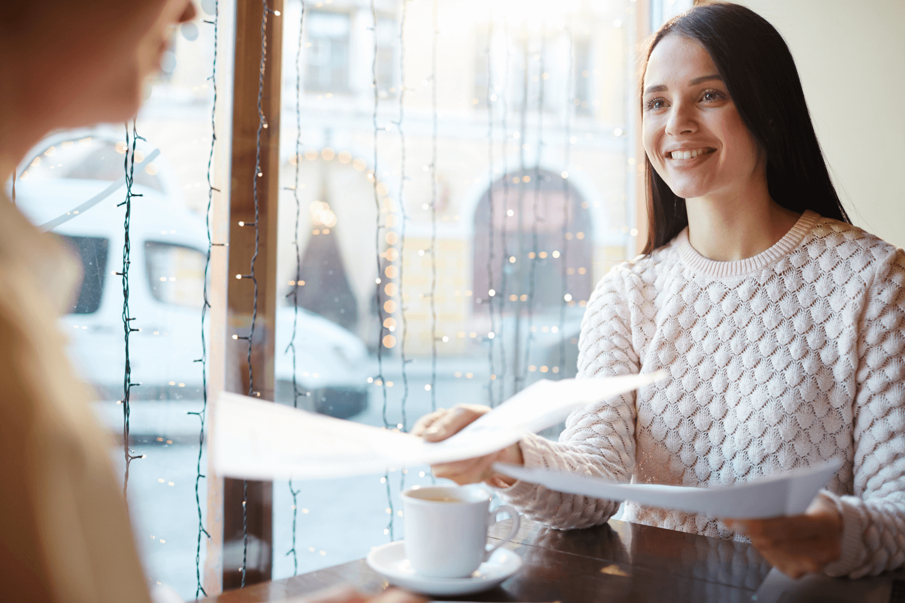 Woman hands resume and cover letter to another woman in a cafe